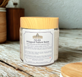 Jar of Calma Whipped Tallow Balm with wooden lid on a wooden surface